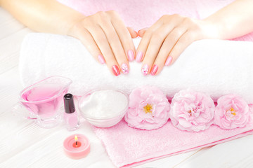 beautiful pink manicure with tea rose on the white wooden table. spa