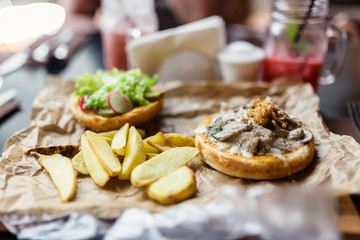 Burger with pieces of beef, fried onions, potatoes and vegetables.