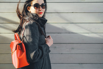 Long hair girl near wooden wall with red backpack