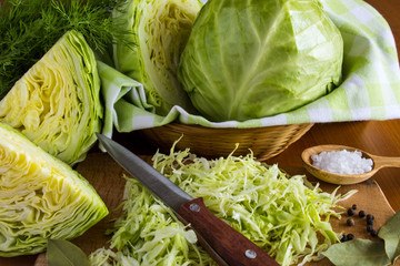 Cabbage and chopped cabbage on the light brown wooden background