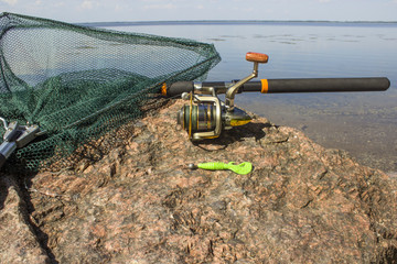 Obraz premium Spinning with bait and sachek on a stone by the river