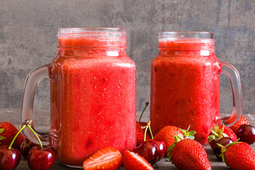 strawberry and cherry smoothie in glass jar with fresh fruits