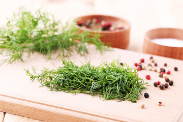 Green dill with pepper on brown cutting board
