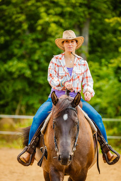 Cowgirl doing horse riding on countryside meadow