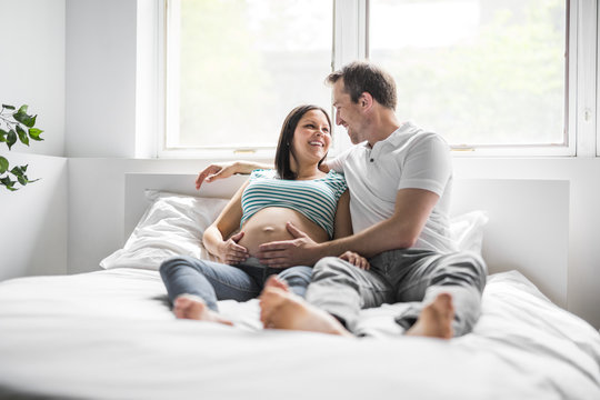 Young parents in bed expecting a little baby, Romantic moments for pregnant couple