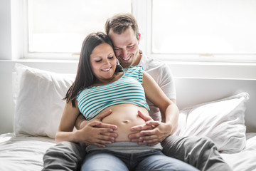 Young parents in bed expecting a little baby, Romantic moments for pregnant couple