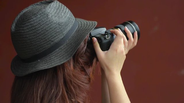 A girl in a hat makes photos with a DSLR camera. Close-up.