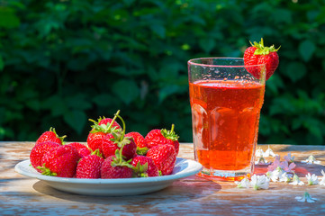 glass with strawberry juice and berries isolated on blur background