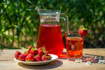 glass with strawberry juice and berries isolated on blur background