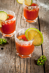 Mexican traditional alcohol drink. Sangrita, with tequila, tomato juice, hot spices, chili and lime.Analogous bloody mary. On rustic wooden table, copy space