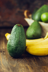 Avocado and banana over brown wooden background.