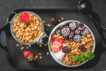Healthy breakfast. Summer berries and fruits. Homemade Greek yogurt with granola, blackberries, strawberries and mint. On a black stone table, with the ingredients. Top view copy space