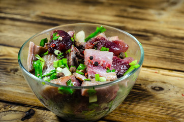 Herring with spices in glass bowl on wooden table