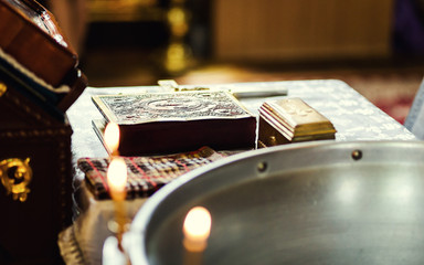 church utensil on an altar, glans, cross on the church altar,the Bible on the table,ceremony of water baptism,Orthodox priest holds a bible on a table with various objects needed for baptism
