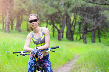 Fototapeta na wymiar Sports woman with a bicycle in the forest. Summer bike ride, free space for your text