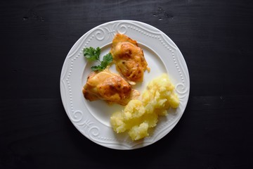 Chicken breast baked with cheese on a white plate, wooden board, close up view