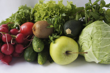 Green vegetables, lettuce, herbs and fruits at border of image with copy space for text. Cabbage, zucchini, cucumbers, radish, tomatoes, kiwi, spinach, parsley, mints and lettuce. 