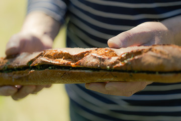 Garlic and fresh herbs olive oil baguette in man hands, outdoors party