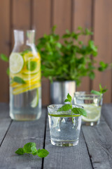Water with lime and mint in glasses on a old wooden table