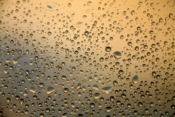 Rain drops on window with sunset light in background