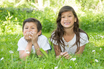 Two young children in a park girl and boy lying on grass