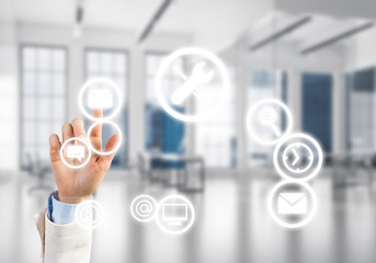 Modern office interior and close of businesswoman hand choosing symbol on application interface