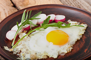 Toasted egg with onions, decorated with arugula and radish.