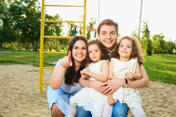 Happy family with children on a swing at the playground.