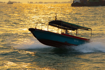a simple speedboat cruising through the sea riding the wave during the sunset
