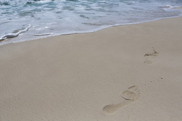 Footsteps on the beach. Footprints composed to the right side. Copy space.