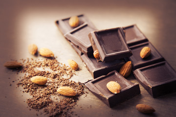 The broken pieces of nut chocolate. Grated chocolate on a brown background