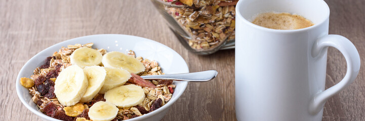 Müsli mit frischer Banane und einer Tasse Kaffee