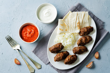 Minced meat sausage with onion, sour cream, pita and red bell pepper relish