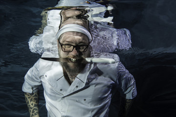A male chef posing with cook's knife underwater
