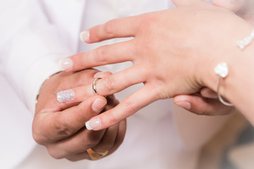 Close up hands of bride and groom putting on a wedding rings