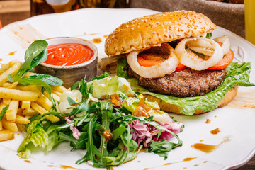 burger on sesame buns with succulent beef patties and fresh salad with arugula on a rustic table