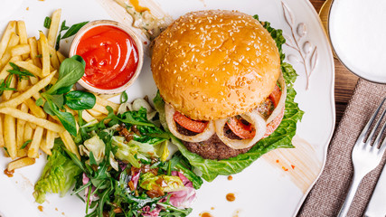 burger on sesame buns with succulent beef patties and fresh salad with arugula on a rustic table