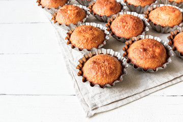 A few muffins in the baking dish. White, wooden background.