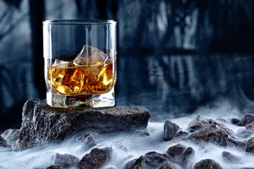 Glass of whiskey and ice.Creative photo glass of whiskey on stone with fog and cold background.Copy...