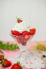 Summer dessert: strawberries and cream on a wooden table