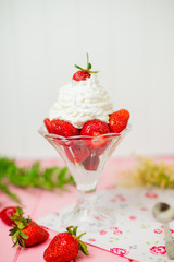 Summer dessert: strawberries and cream on a wooden table