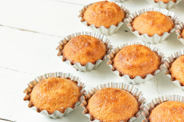 A few muffins in the baking dish. White, wooden background.