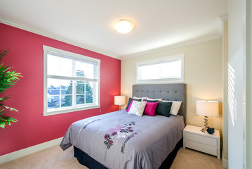 Modern bedroom interior design with a red wall, designer pillows, and a floral duvet cover in a luxury house.