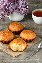 A few muffins on wooden background. A bouquet of lilacs, the broken cupcake.