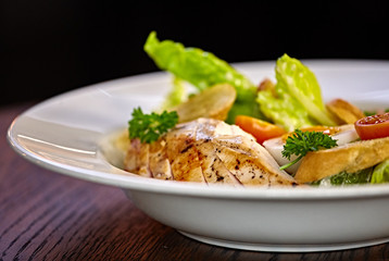 Chicken salad with leaf vegetables, chard, eggs, bulgur and cherry tomatoes. Chicken Caesar Salad. Caesar Salad with grilled chicken on plate. Grilled chicken breasts and fresh salad in plate.