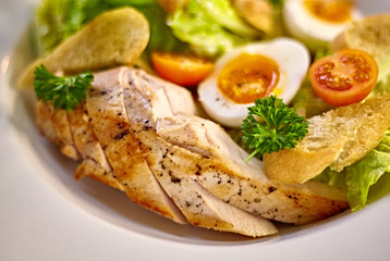 Chicken salad with leaf vegetables, chard, eggs, bulgur and cherry tomatoes. Chicken Caesar Salad. Caesar Salad with grilled chicken on plate. Grilled chicken breasts and fresh salad in plate.
