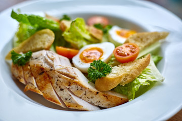 Chicken salad with leaf vegetables, chard, eggs, bulgur and cherry tomatoes. Chicken Caesar Salad. Caesar Salad with grilled chicken on plate. Grilled chicken breasts and fresh salad in plate.