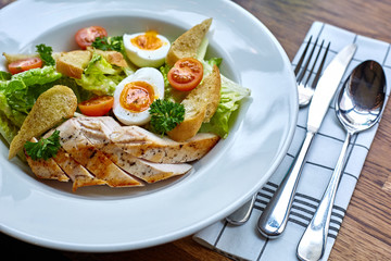Chicken salad with leaf vegetables, chard, eggs, bulgur and cherry tomatoes. Chicken Caesar Salad. Caesar Salad with grilled chicken on plate. Grilled chicken breasts and fresh salad in plate.