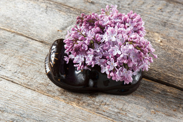 A bouquet of flowers of lilac in a ceramic Shoe.
