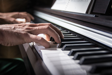 Obraz premium Male hand playing the keys of piano